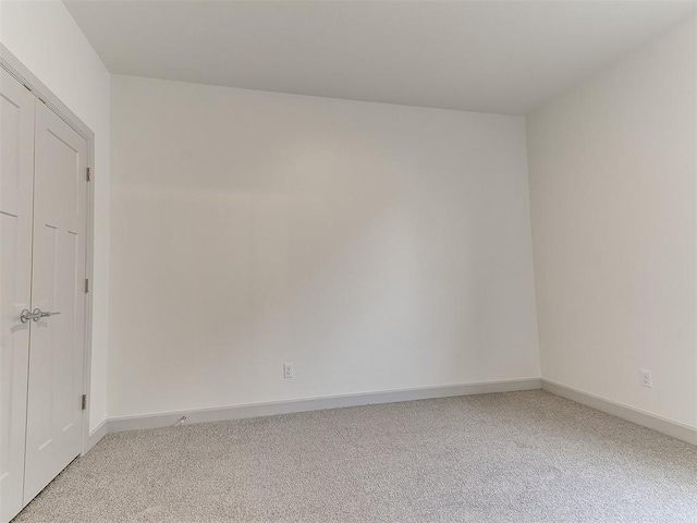 unfurnished room with light carpet and baseboards