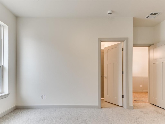 carpeted empty room featuring baseboards and visible vents