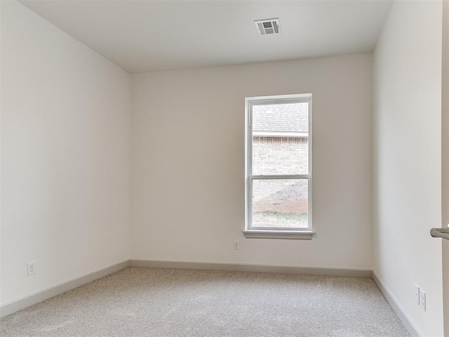 empty room with carpet flooring, visible vents, and baseboards