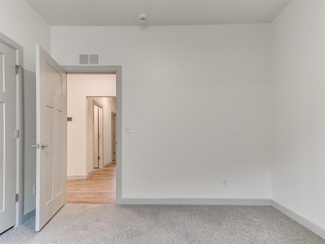 spare room with baseboards, visible vents, and light colored carpet