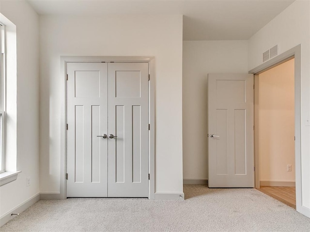 unfurnished bedroom featuring carpet floors, a closet, visible vents, and baseboards