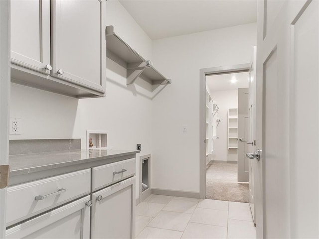 interior space with light tile patterned floors, light carpet, washer hookup, cabinet space, and electric dryer hookup