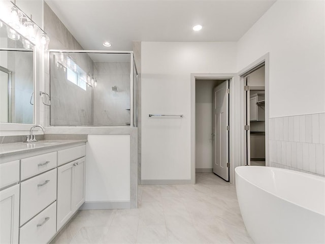 full bathroom featuring a stall shower, a spacious closet, vanity, a freestanding tub, and tile walls