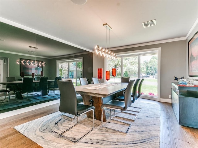 dining area featuring an inviting chandelier, visible vents, wood finished floors, and ornamental molding