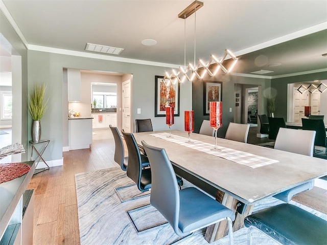 dining area featuring ornamental molding, plenty of natural light, visible vents, and light wood-style floors