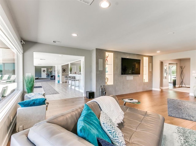 living room with baseboards, wood finished floors, visible vents, and recessed lighting