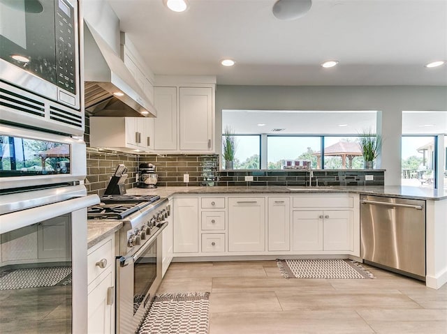 kitchen with stainless steel appliances, plenty of natural light, a sink, and wall chimney exhaust hood