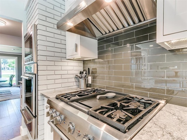 kitchen with wall chimney exhaust hood, appliances with stainless steel finishes, white cabinets, and a warming drawer