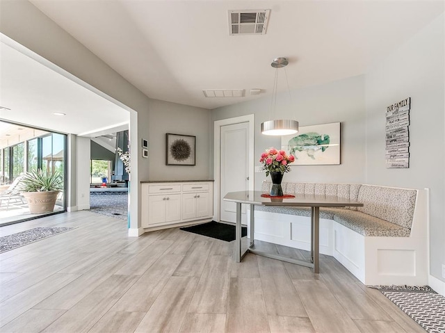 hallway featuring light wood finished floors, visible vents, and baseboards