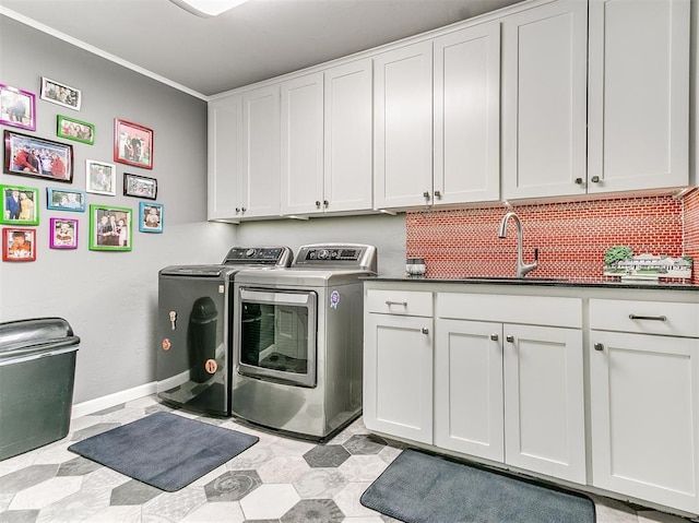 washroom with washer and clothes dryer, a sink, cabinet space, and baseboards