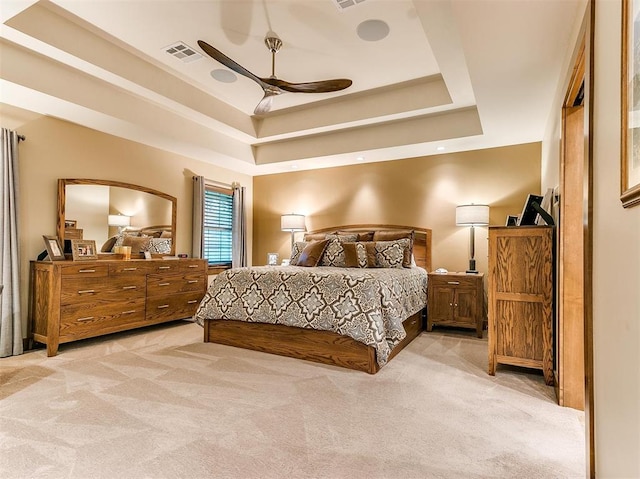 bedroom featuring light colored carpet, a tray ceiling, and visible vents