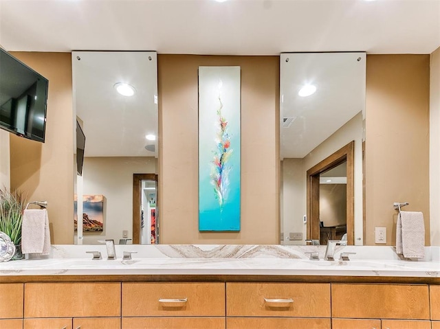 ensuite bathroom with double vanity, ensuite bath, and a sink