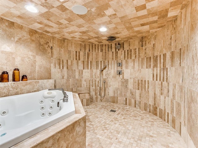 bathroom featuring a jetted tub, a tile shower, and tile walls