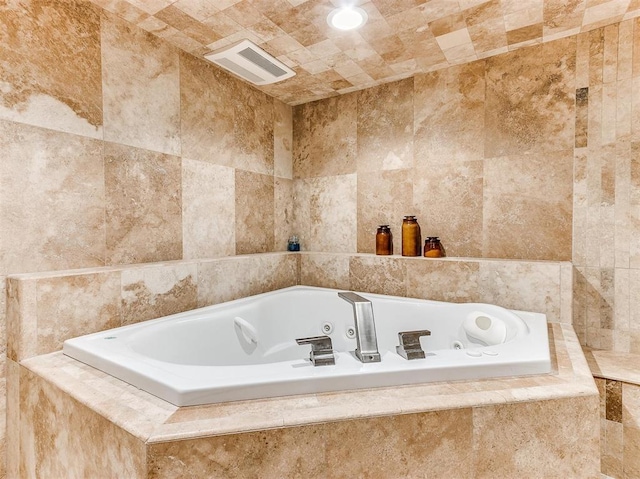 full bath with visible vents, tile walls, and a whirlpool tub