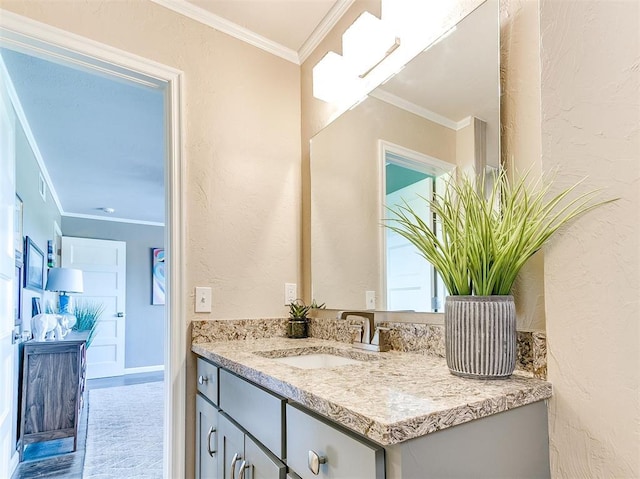 bathroom with vanity, ornamental molding, and a textured wall