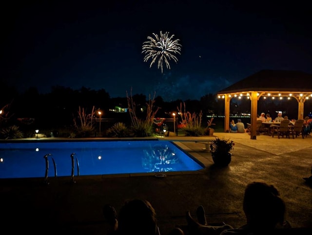 pool at twilight with a gazebo, a patio area, and an outdoor pool