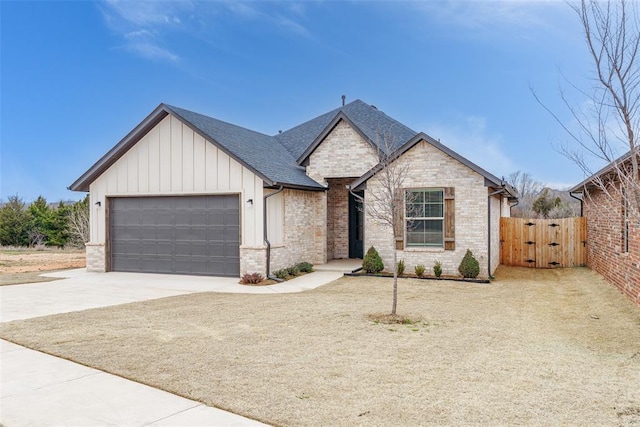 view of front of property with a gate, an attached garage, concrete driveway, board and batten siding, and brick siding