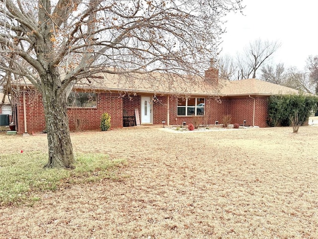 view of front of property featuring brick siding, a chimney, a shingled roof, and a front yard