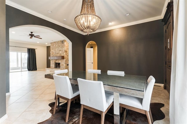 dining room with arched walkways, ornamental molding, and a stone fireplace