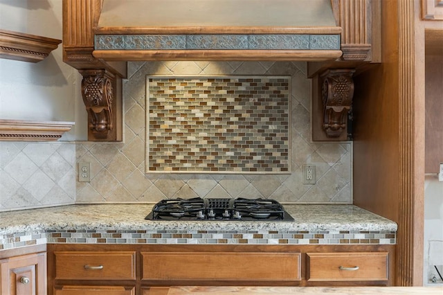 kitchen with tasteful backsplash, brown cabinets, extractor fan, light countertops, and black gas stovetop