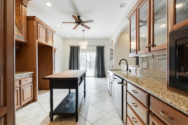 kitchen with light tile patterned floors, tasteful backsplash, light stone counters, and brown cabinetry