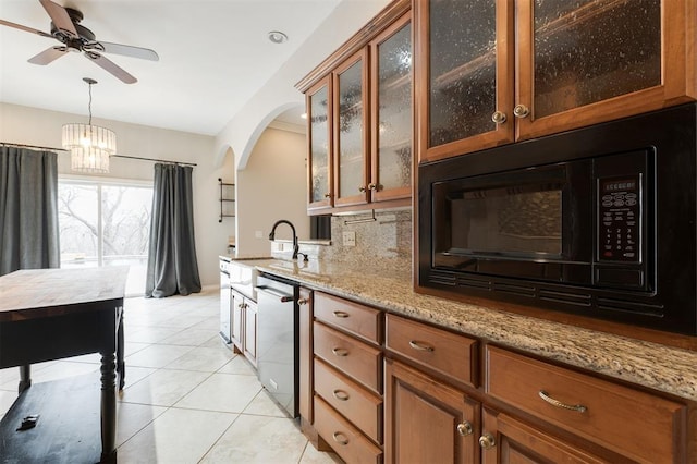 kitchen with light stone counters, brown cabinets, stainless steel dishwasher, a sink, and black microwave