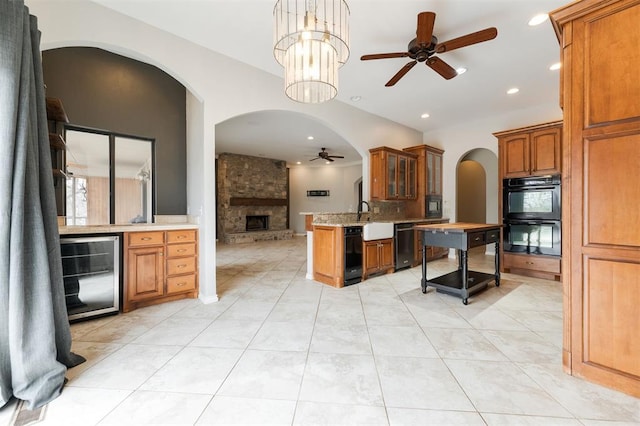 kitchen featuring dobule oven black, brown cabinetry, a ceiling fan, wine cooler, and open floor plan