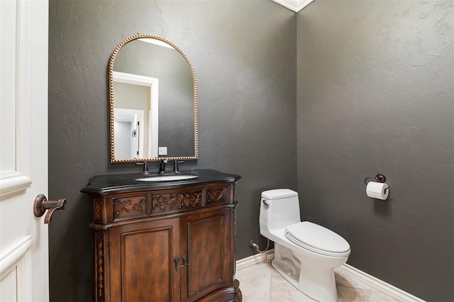 half bathroom with baseboards, a textured wall, toilet, tile patterned flooring, and vanity