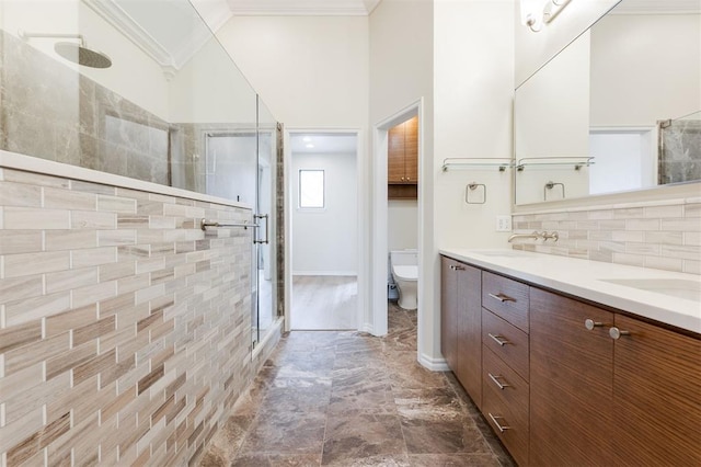 full bathroom with decorative backsplash, toilet, ornamental molding, a stall shower, and a sink