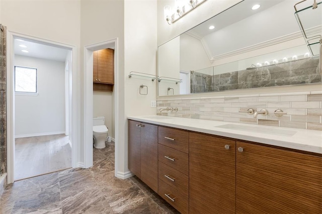 bathroom featuring double vanity, toilet, decorative backsplash, a sink, and a tile shower