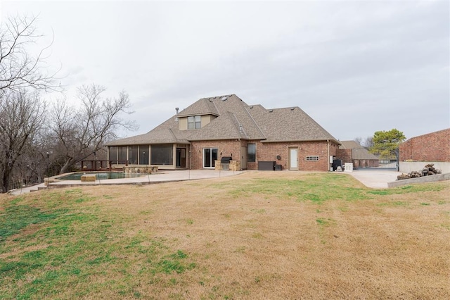 back of property featuring brick siding, a sunroom, a lawn, an outdoor pool, and a patio area