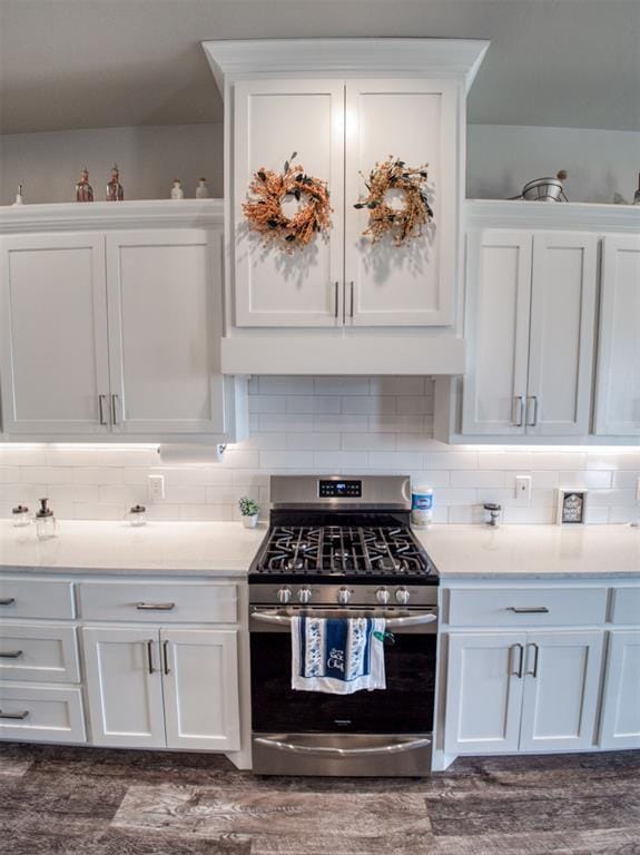 kitchen with backsplash, under cabinet range hood, light countertops, gas stove, and white cabinetry