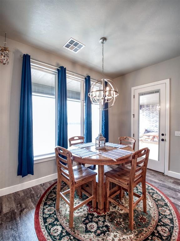 dining space with visible vents, baseboards, wood finished floors, and a chandelier