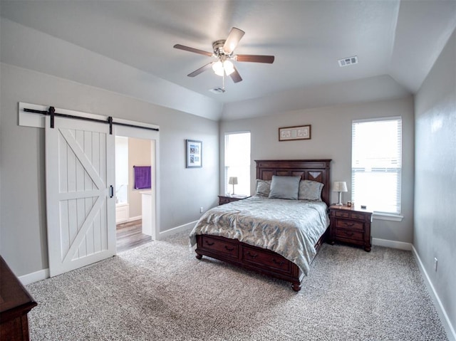 carpeted bedroom featuring visible vents, baseboards, a barn door, and vaulted ceiling