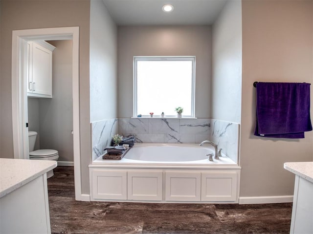 full bathroom with a garden tub, baseboards, toilet, and vanity