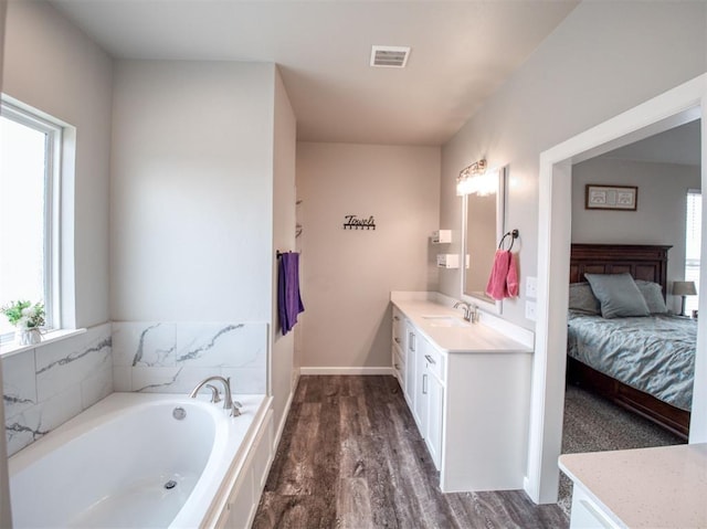 ensuite bathroom featuring visible vents, ensuite bathroom, wood finished floors, a bath, and vanity