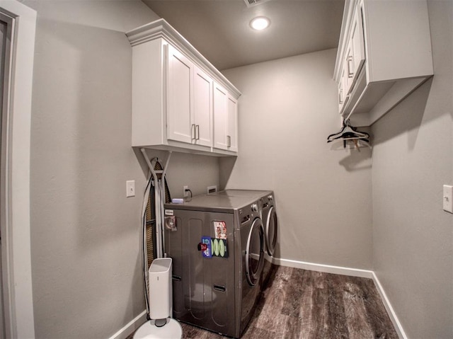 clothes washing area with washer and dryer, baseboards, cabinet space, and dark wood-type flooring