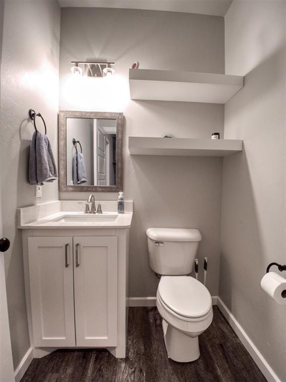 half bath with toilet, wood finished floors, and baseboards