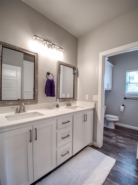 full bathroom with a sink, toilet, wood finished floors, and double vanity