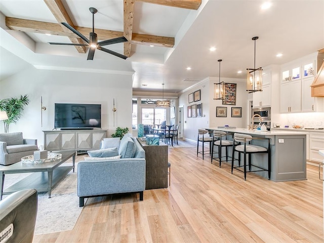 living room with ceiling fan, coffered ceiling, baseboards, light wood-style floors, and beamed ceiling