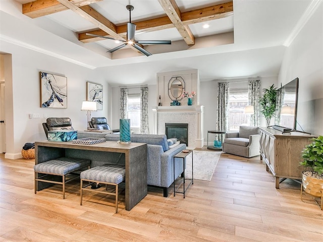 living area with a glass covered fireplace, coffered ceiling, plenty of natural light, and wood finished floors