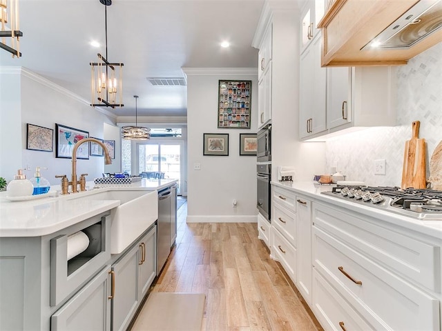 kitchen with stainless steel appliances, visible vents, light countertops, custom exhaust hood, and crown molding