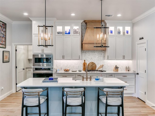 kitchen featuring stainless steel appliances, light wood finished floors, light countertops, and crown molding