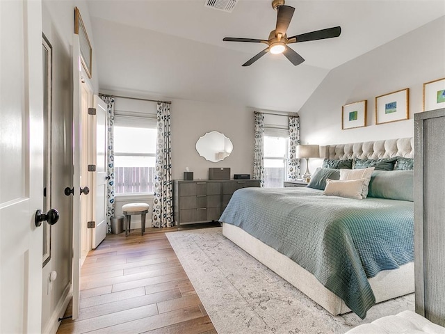 bedroom with lofted ceiling, ceiling fan, visible vents, and wood finished floors