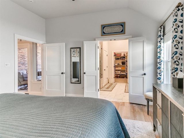 bedroom with vaulted ceiling and light wood-style floors