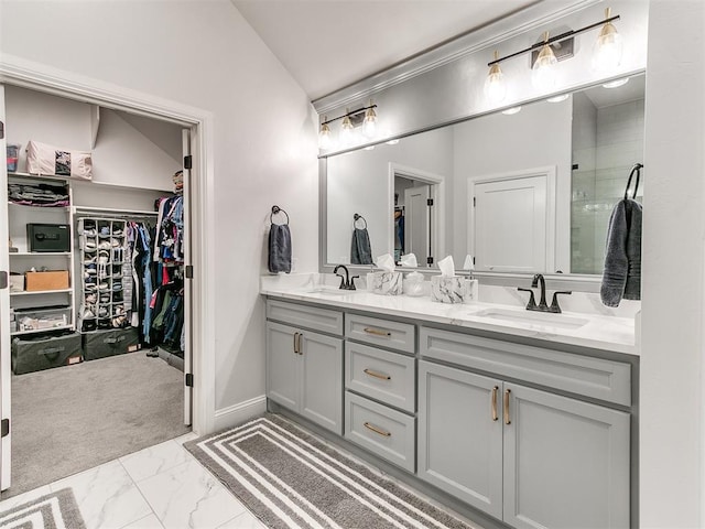 full bath featuring lofted ceiling, a sink, a spacious closet, marble finish floor, and double vanity