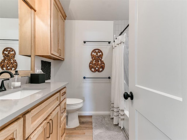 full bath with toilet, baseboards, wood finished floors, and vanity