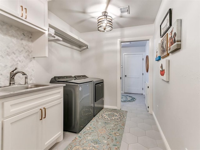 laundry area featuring light tile patterned floors, washing machine and dryer, a sink, visible vents, and cabinet space