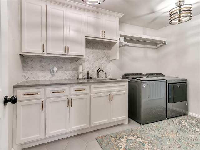 washroom with cabinet space, washing machine and dryer, light tile patterned floors, and a sink