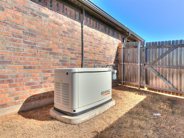 details featuring a gate, fence, a power unit, and brick siding